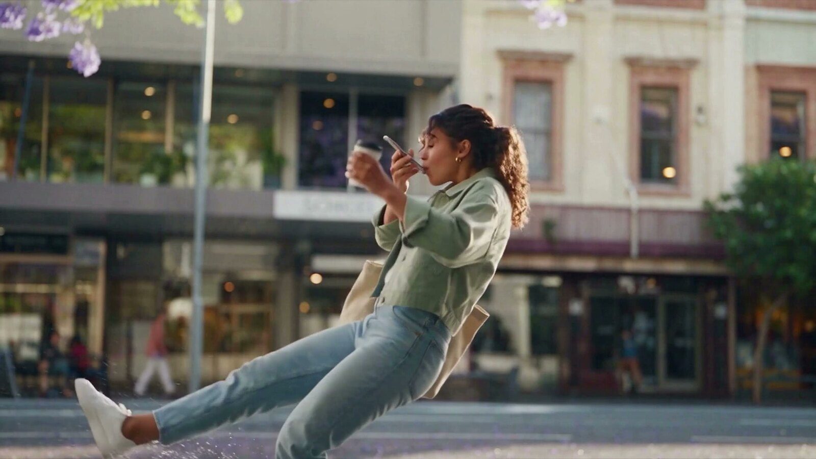 A woman slipping on a wet Brisbane street, caught in mid-air under jacaranda trees